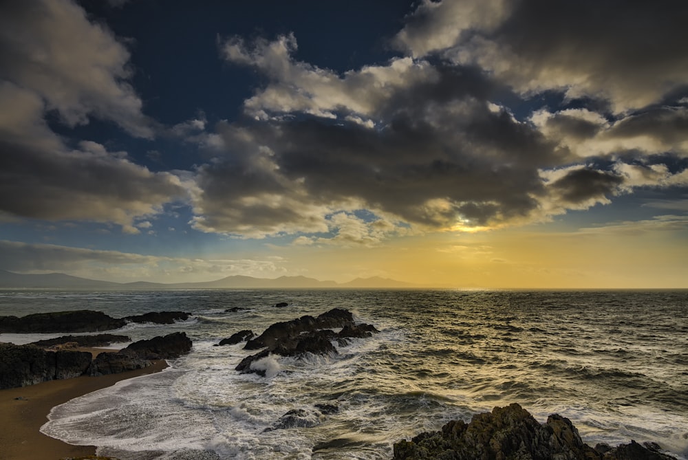 sea wave splashing on rock formation during golden hour