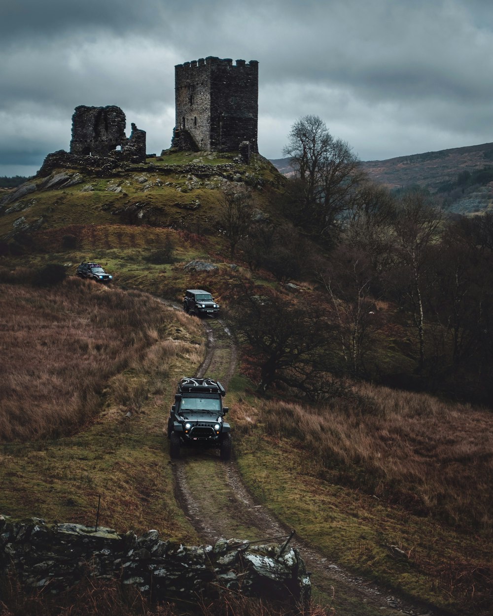 vehicles on road viewing brown ruin castle under white and gray sky