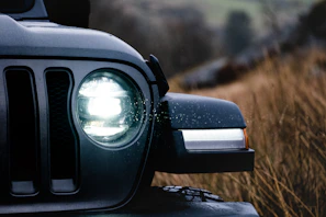 Close-up of the Jaecoo J8’s front grille and headlights against a backdrop of rolling hills.