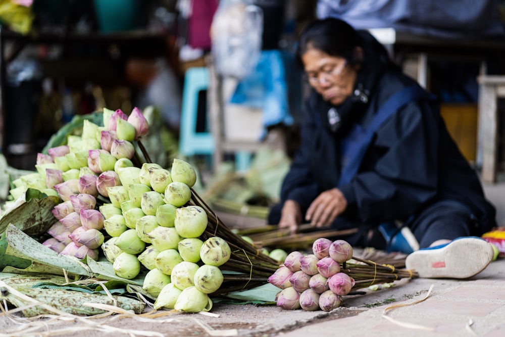 a woman sitting on the ground next to a pile of onions