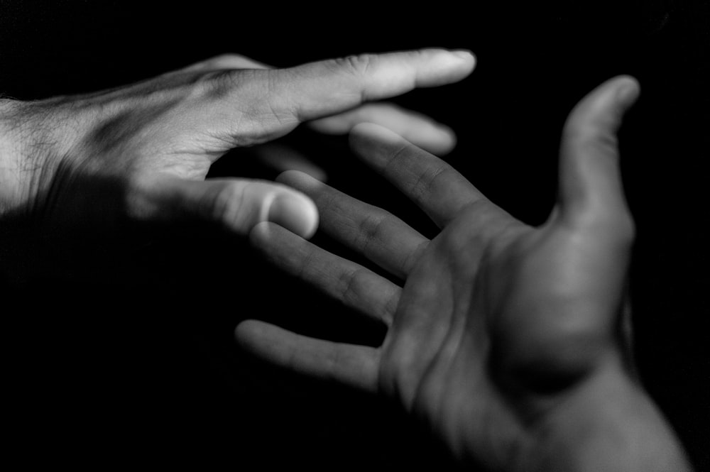 a black and white photo of two hands reaching towards each other