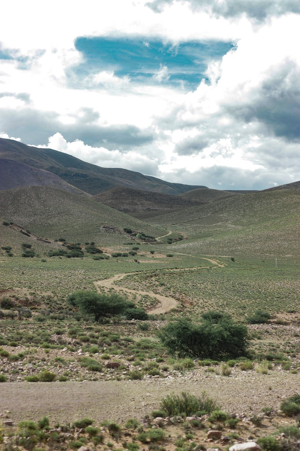 landscape photography of green field viewing mountain under white and blue sky