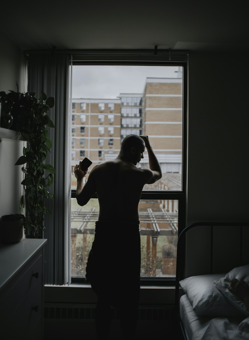 man standing by the window beside bed