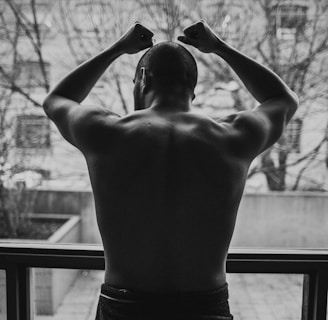 topless man standing near window