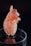A detailed 3D printed model of a human heart with intricate, lattice-like patterns is displayed on a transparent circular stand. The heart is primarily light orange in color, situated against a dark background, which highlights its features and structure.