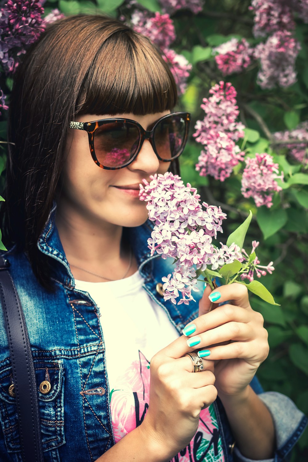 woman smiling and smelling pink flowers