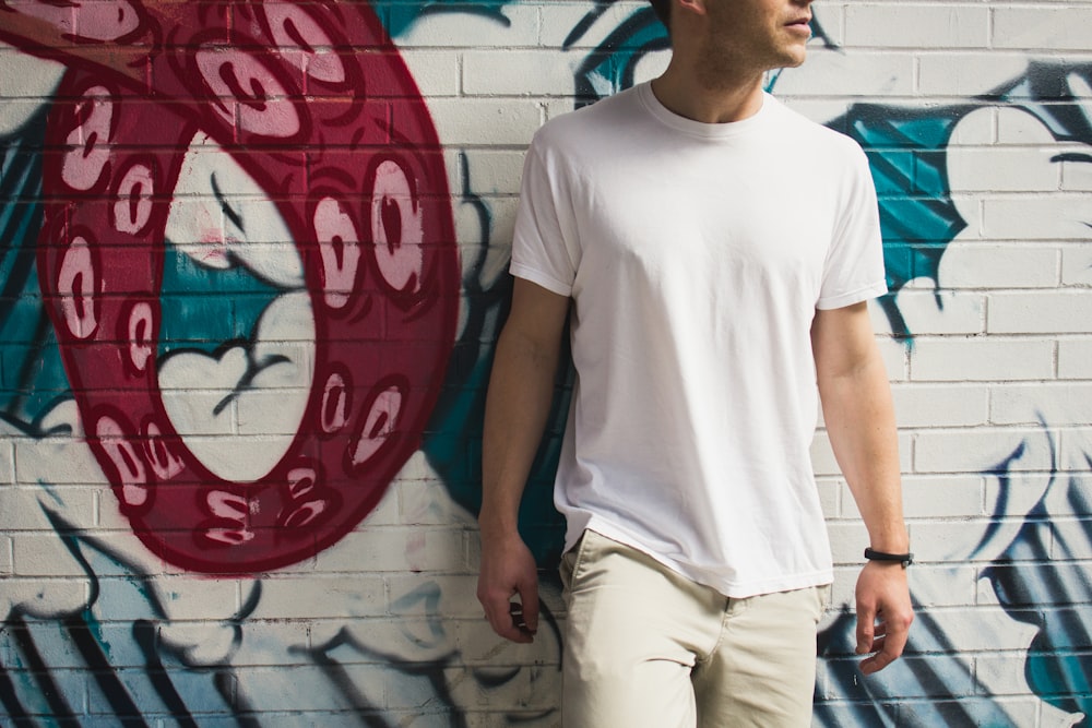 man wearing white shirt standing near the wall