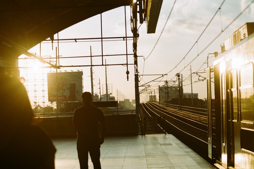 Fotografía de la silueta del hombre de pie cerca de los ferrocarriles