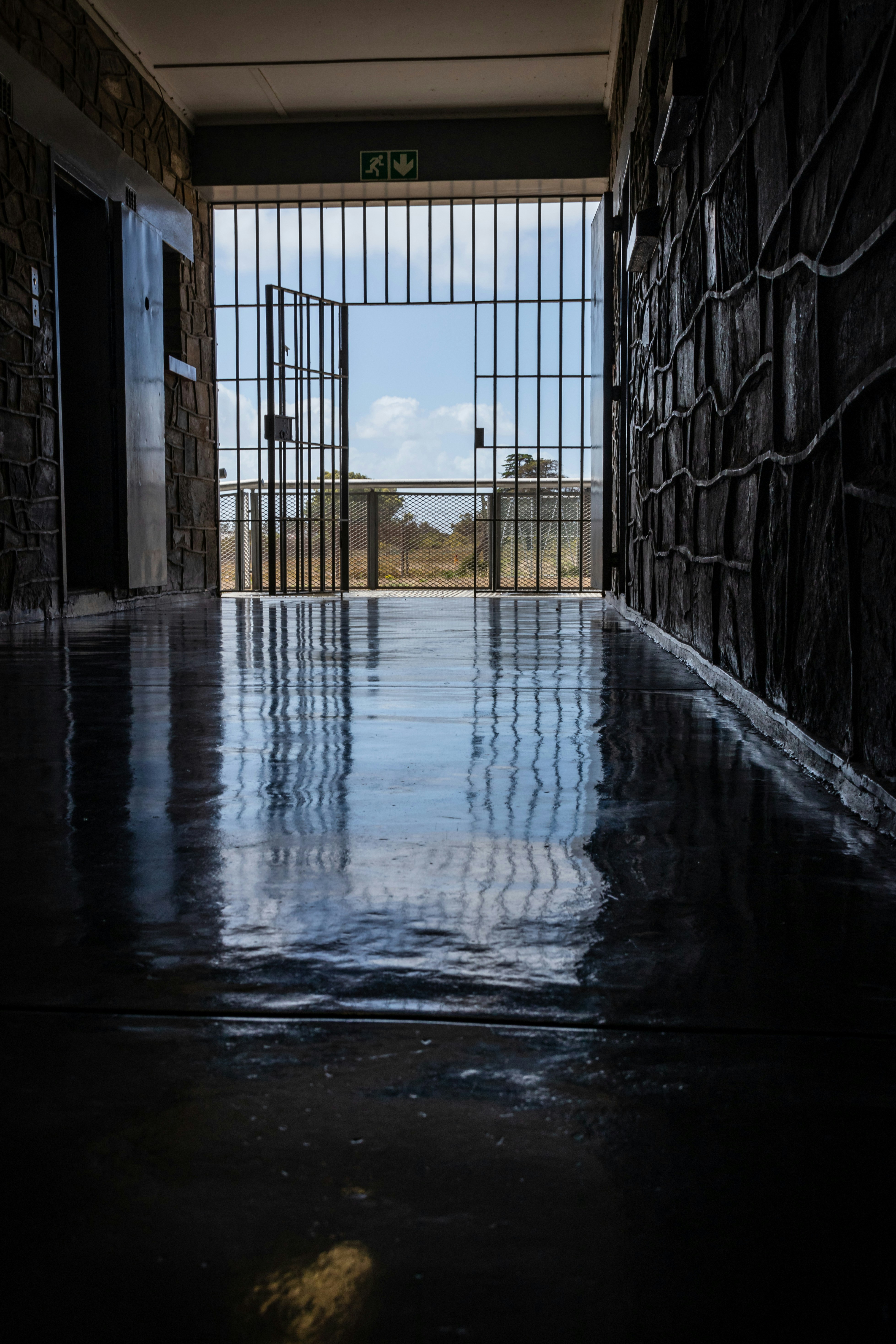 Wet Hallway Leading To An Open Gate At Daytime Photo Free Prison