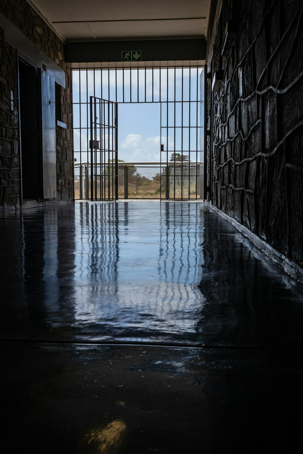 Wet Hallway Leading To An Open Gate At Daytime Photo Free Prison