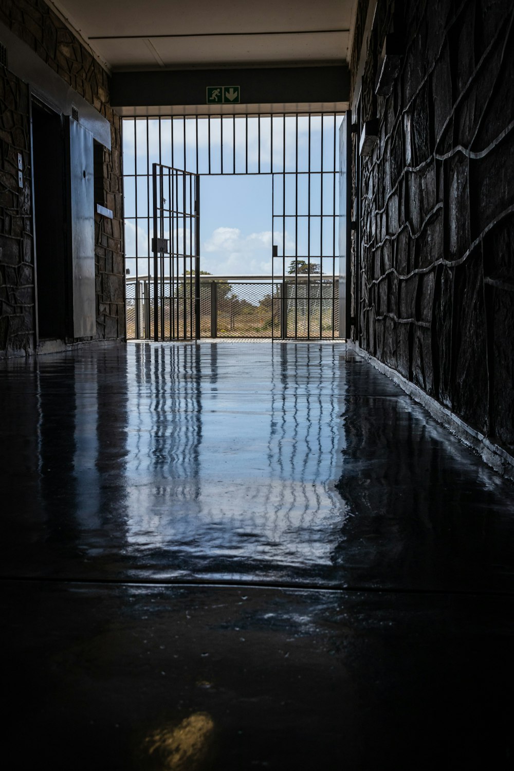 wet hallway leading to an open gate at daytime