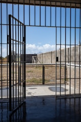 A prison gate with shadows of inmates in the background.