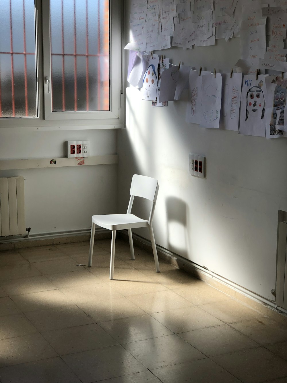 empty armless chair by wall with hanging papers