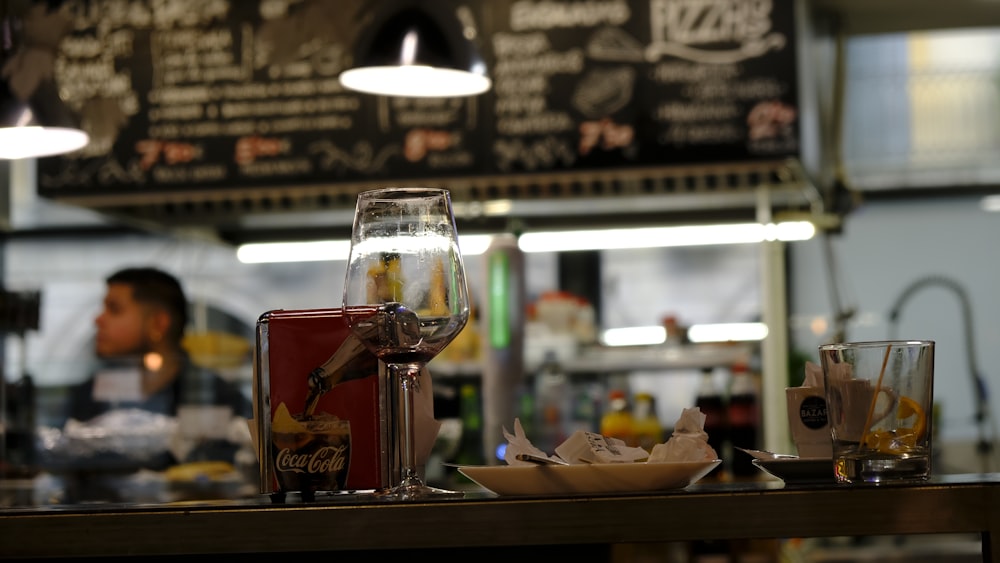 empty clear long-stem wine glass near plate with food on top on a wooden table