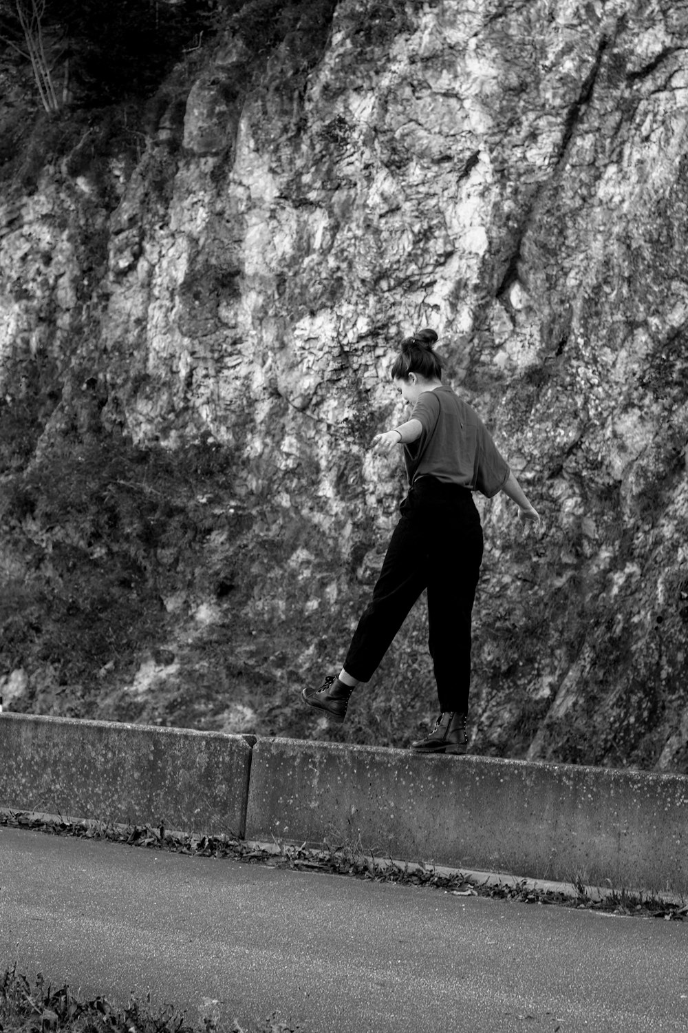 grayscale photography of woman beside mountain rocks