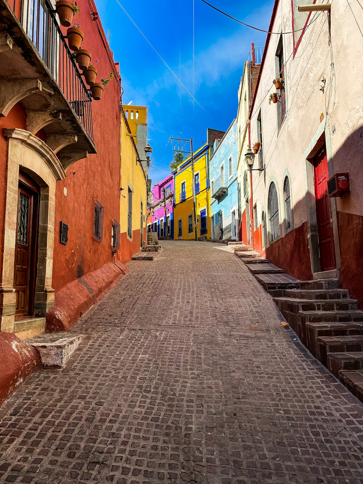 Guanajuato July — cobblestone alley between brightly painted colonial walls, quiet and damp in the rainy season with no visitors in sight