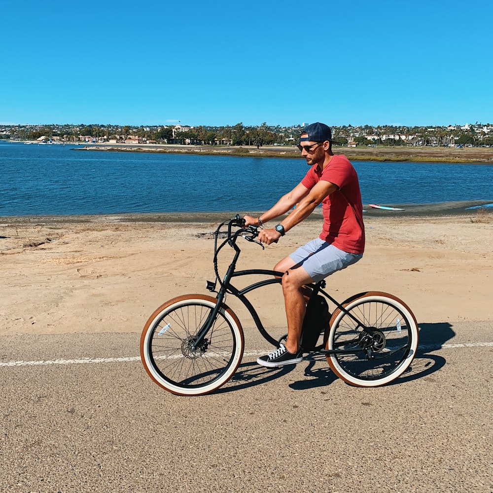 man in red shirt and blue shorts riding beach cruiser