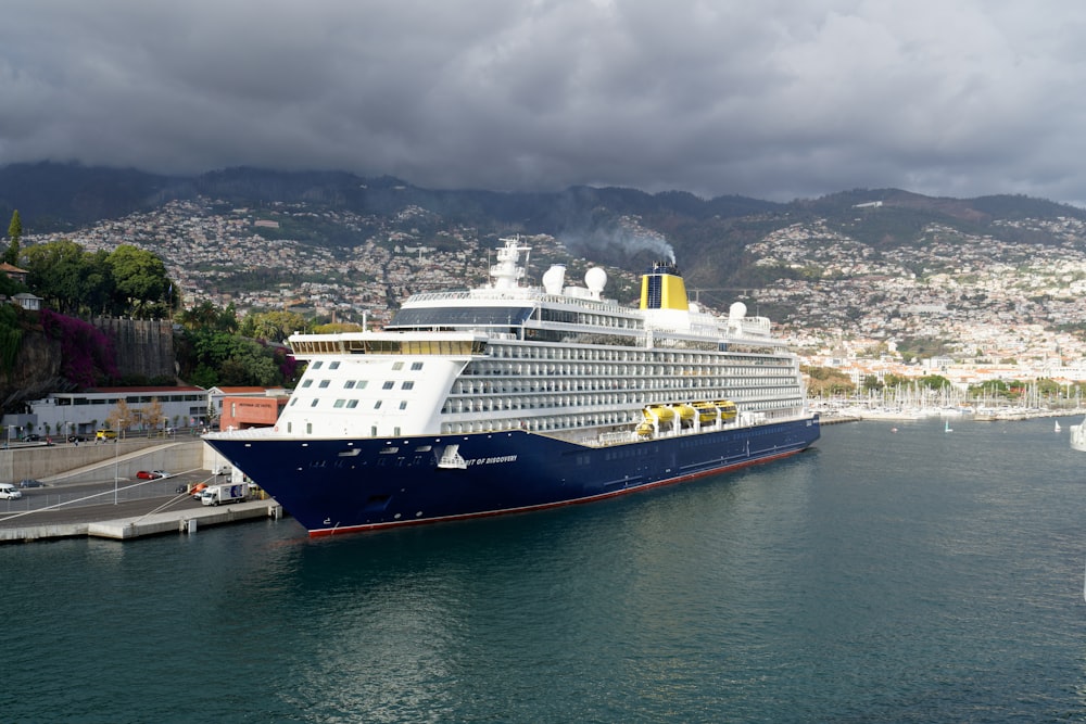 white and blue cruise ship under a dramatic sky