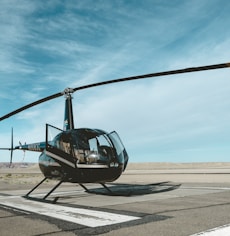 black helicopter on railway under white and blue sky