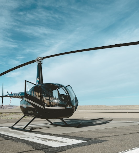 black helicopter on railway under white and blue sky