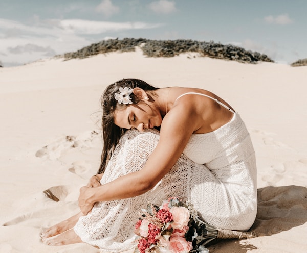 woman in white spaghetti strap dress sitting on sand