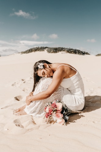 woman in white spaghetti strap dress sitting on sand