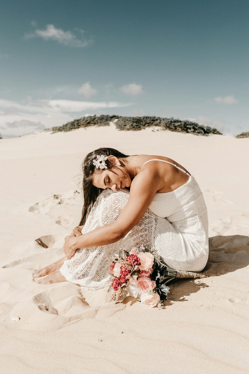 woman in white spaghetti strap dress sitting on sand