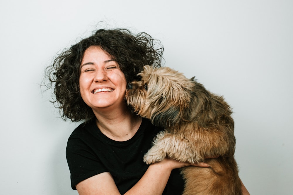 Hund küsst Frau in schwarzem Hemd mit Rundhalsausschnitt