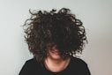 person with curly hair covering face