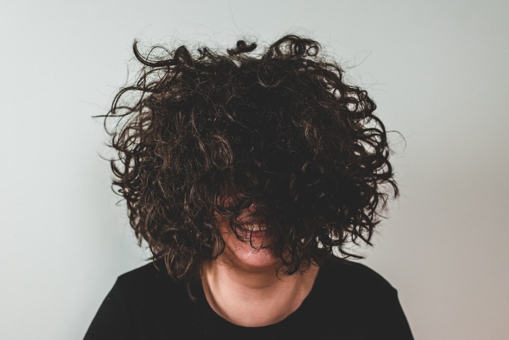 Person mit lockigem Haar, das das Gesicht bedeckt