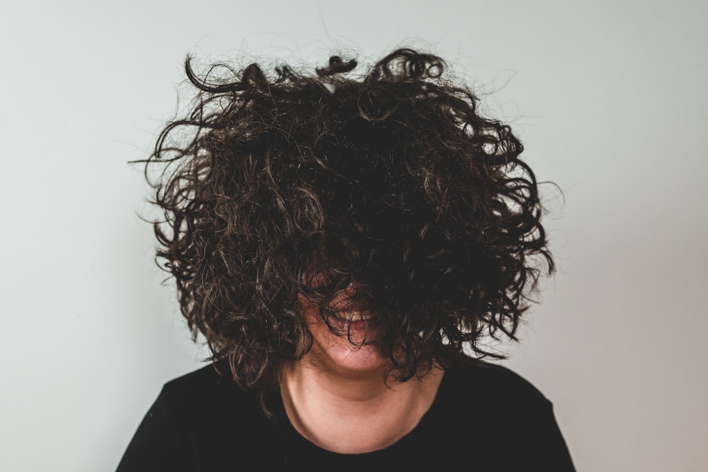 person with curly hair covering face