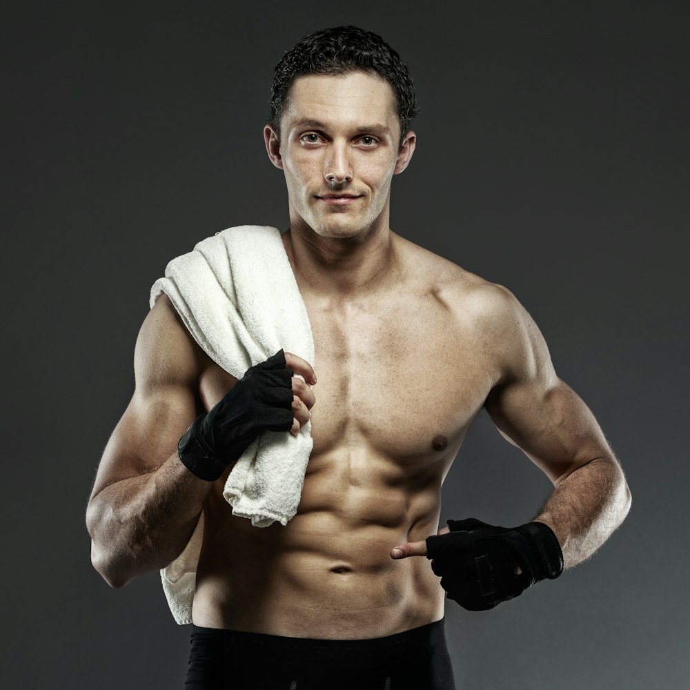 topless man wearing black gloves holding towel