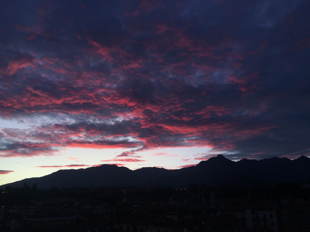 silhouette photography of a mountain under a cloudy sky during daytime