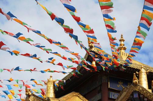 A panoramic view of the Badrinath temple framed by vibrant marigold garlands and fluttering prayer flags.