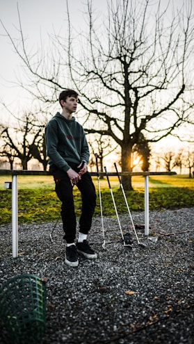 man standing beside railing and golf clubs