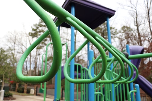 Technician inspecting playground equipment closely with tools