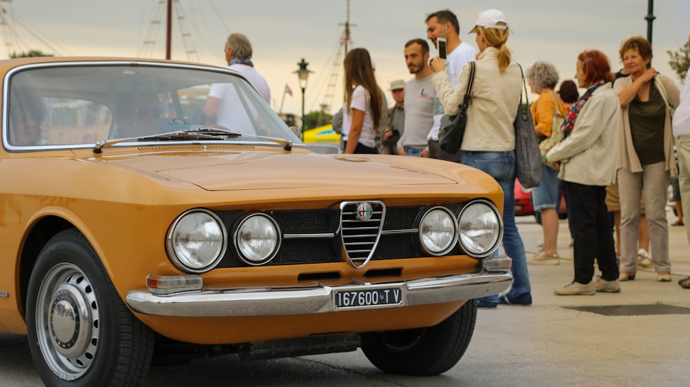 men and women standing beside a yellow car