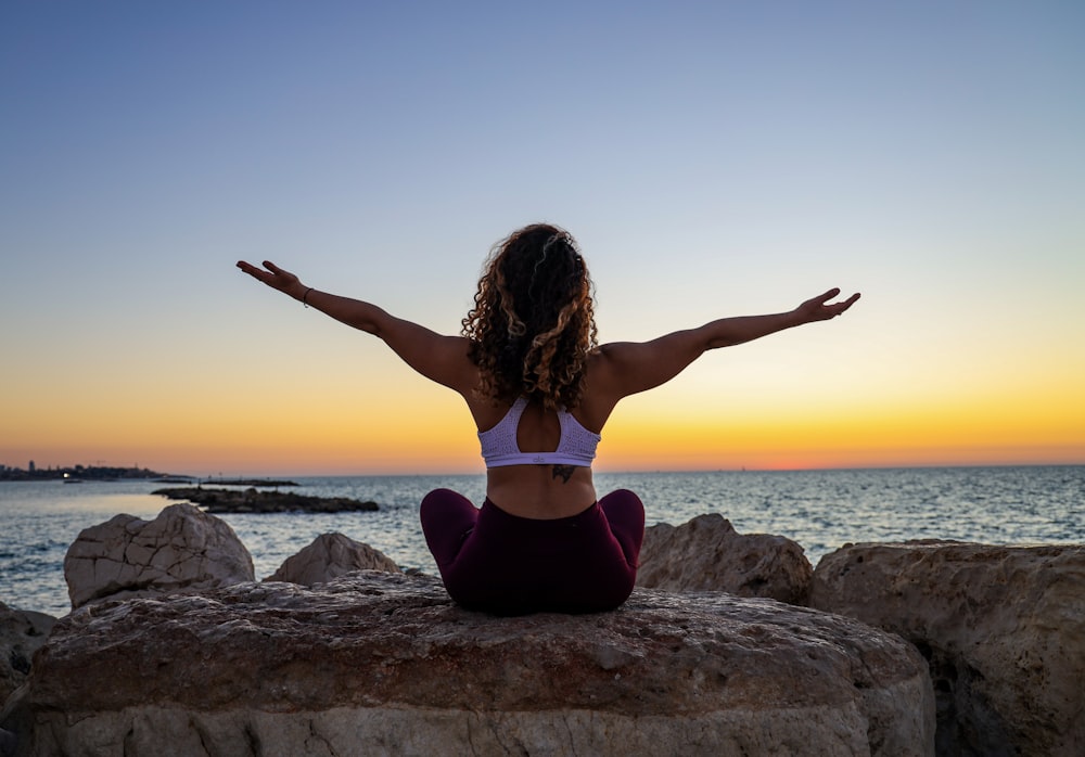 woman sitting on the stone in front of the ocean