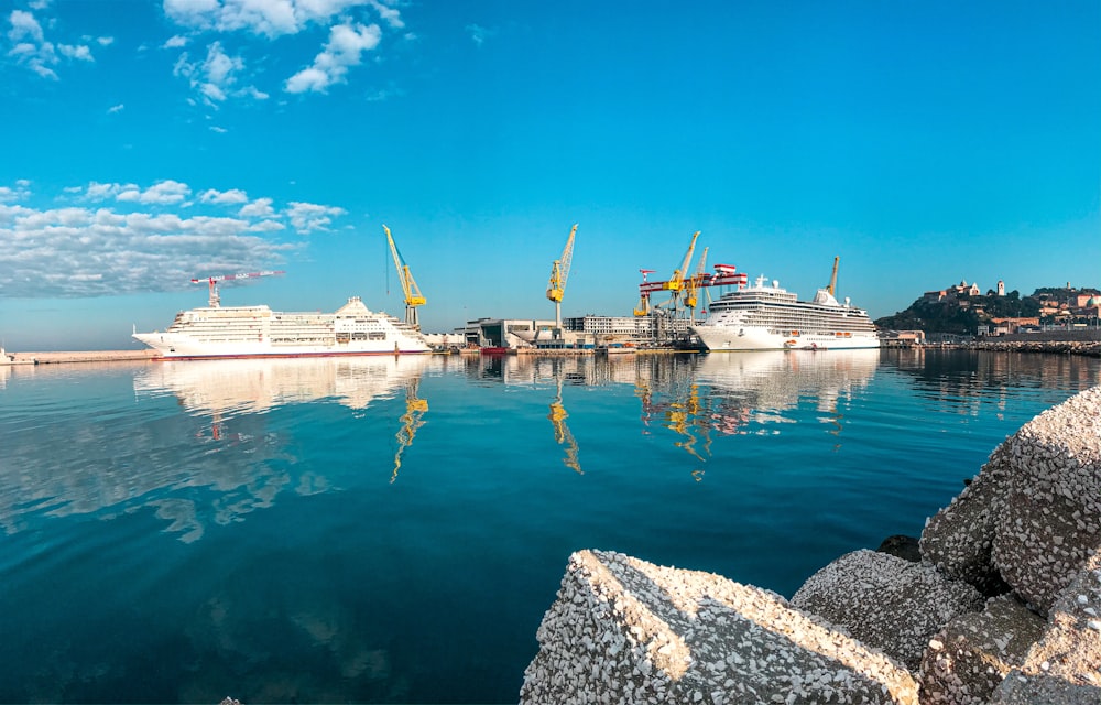 cruiser ships by quay cranes at daytime