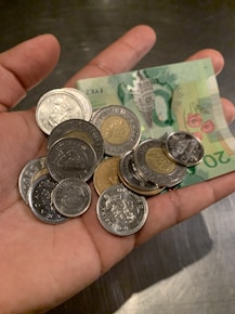 Hand holding euro coins and a €20 bill to show the currency travelers will use throughout Italy