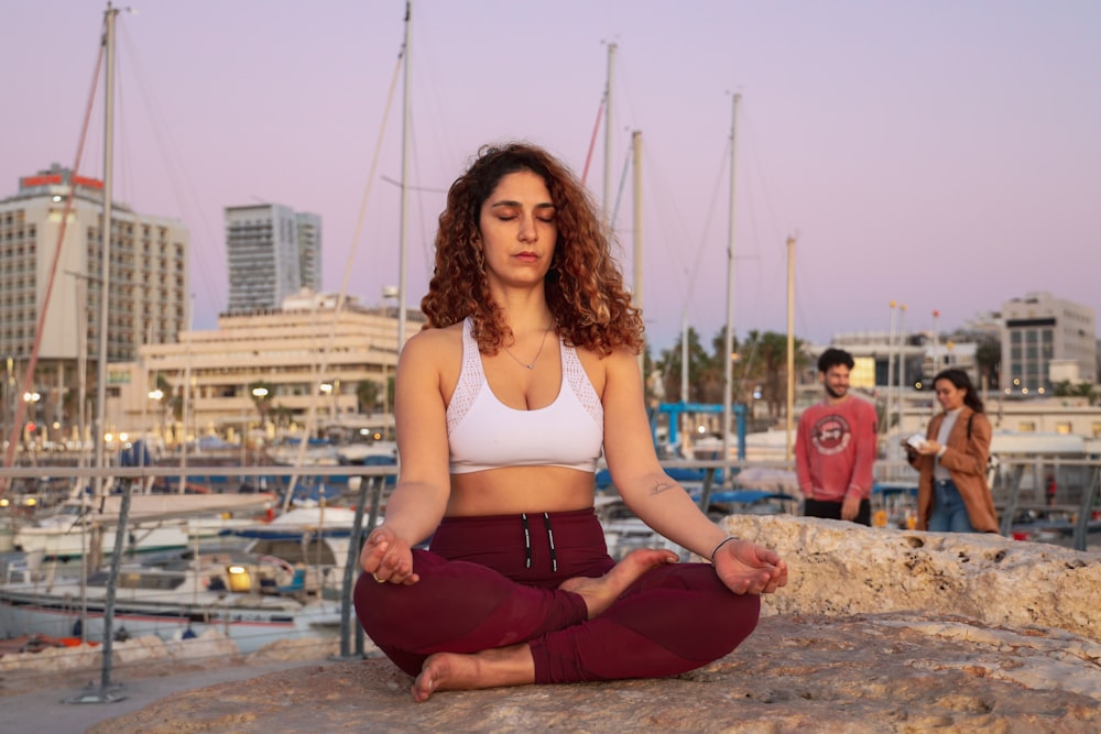 meditating woman in white sports bra and red yoga pants outfit