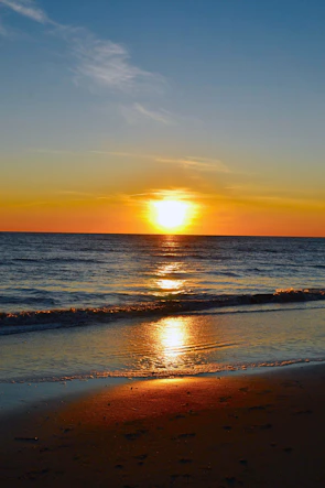 Sunset over the ocean with warm orange and turquoise hues reflecting on the water.