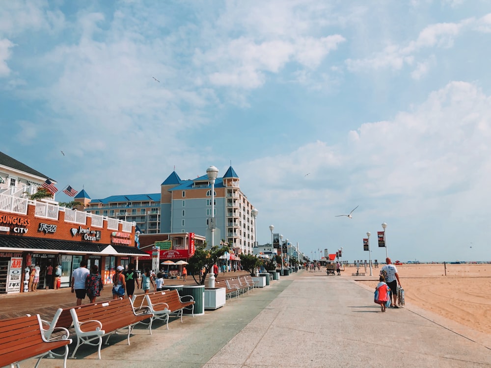 Personas caminando por el paseo marítimo cerca de edificios bajo el cielo blanco y azul