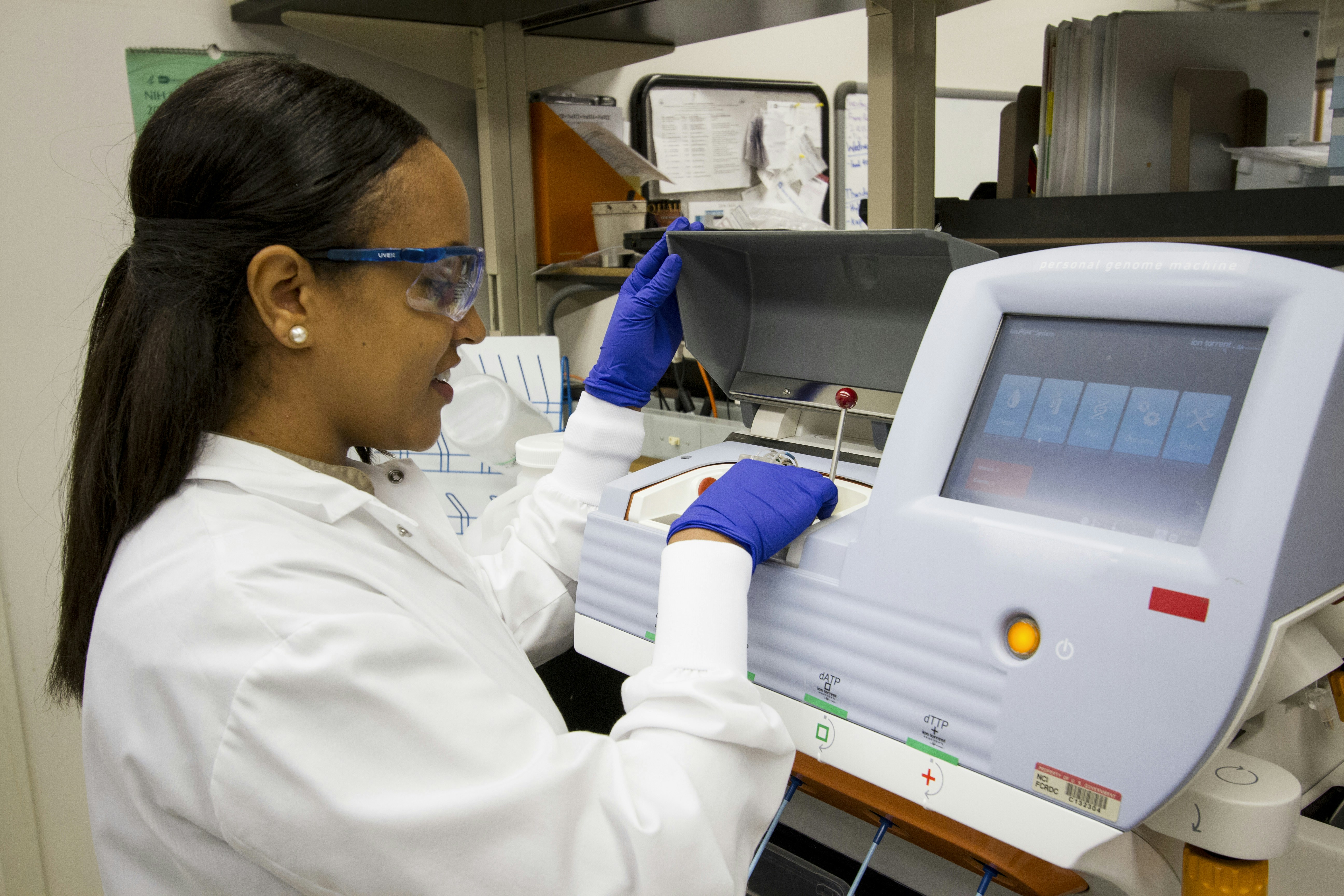 DNA Genotyping and Sequencing. A technician loads DNA samples into a desktop genomic sequencing machine at the Cancer Genomics Research Laboratory, part of the National Cancer Institute's Division of Cancer Epidemiology and Genetics (DCEG). Creator: Daniel Sone