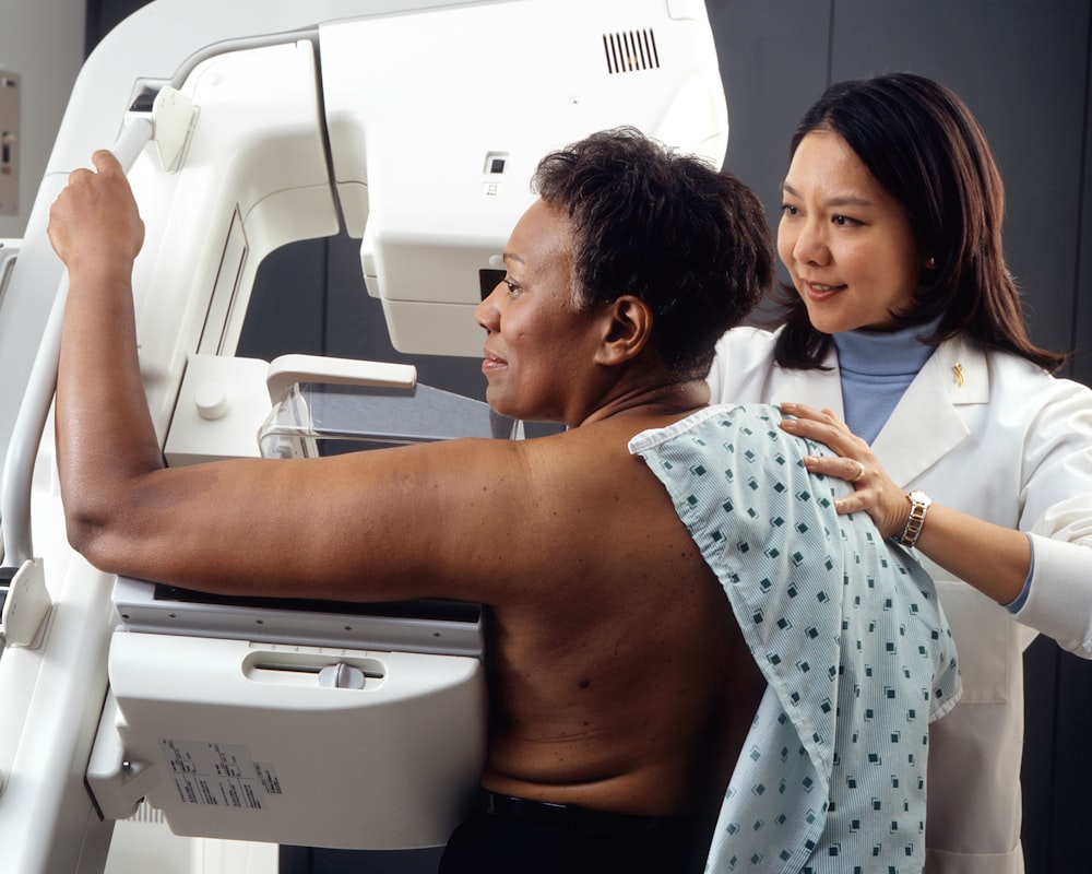 female doctor standing near woman patient doing breast cancer screening