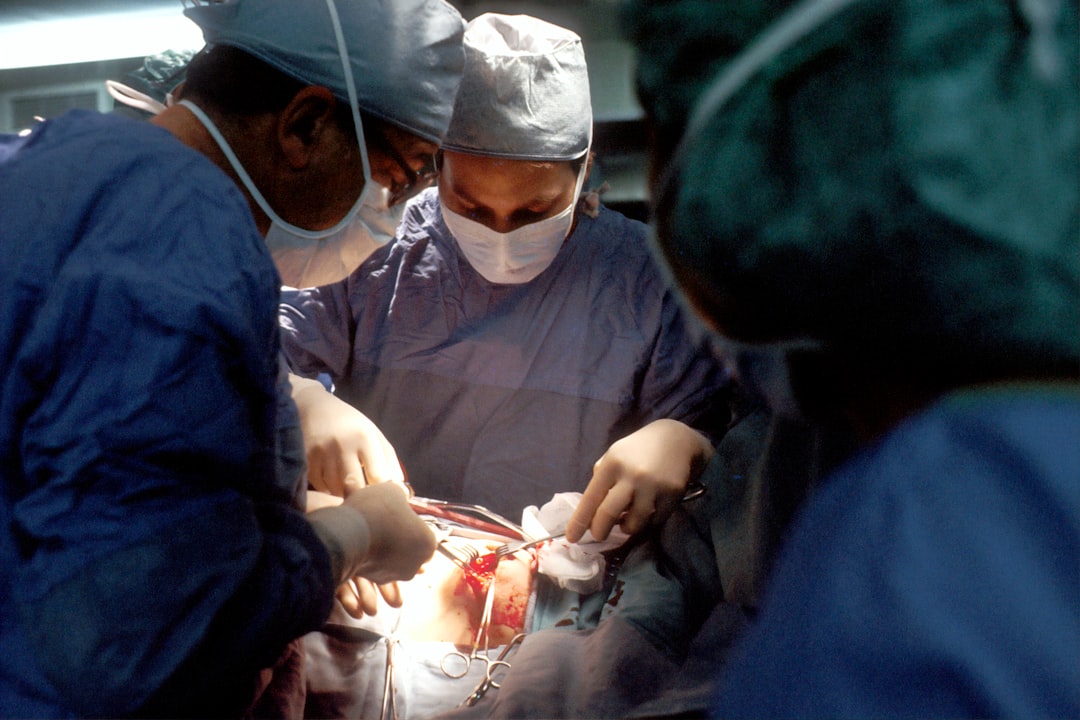 Biopsy. A Caucasian woman patient is being operated on. Her nipple is being incised by the surgeon. The male surgeon and an operating room attendant are visible. A surgical biopsy is being performed to determine exact nature of solid tumor. Creator: Linda Bartlett

