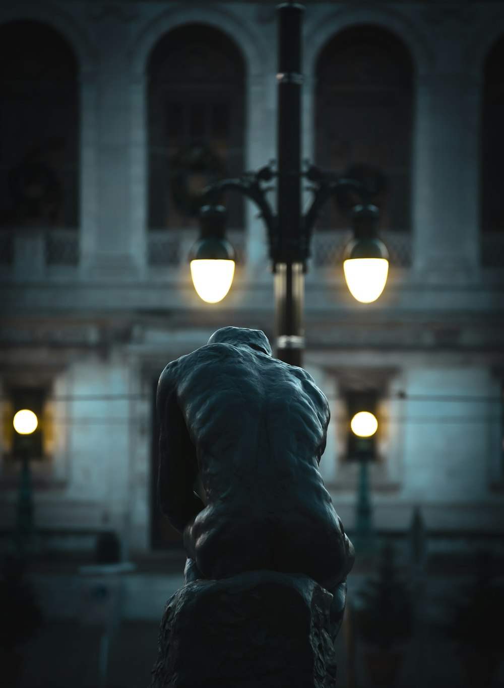 夜間に灯された街灯のそばにある考える人の像