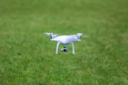 A drone flying over a lush green field capturing aerial footage.