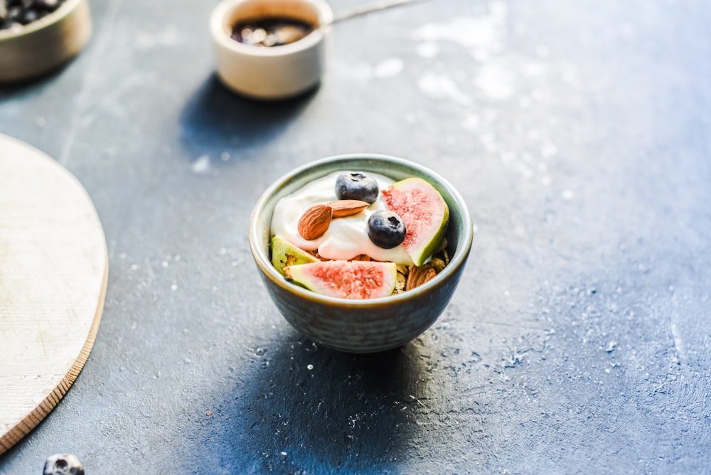 sliced fog fruit with blueberry and almonds in round green ceramic bowl