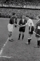 Close-up of a football agent shaking hands with a young player on a stadium background